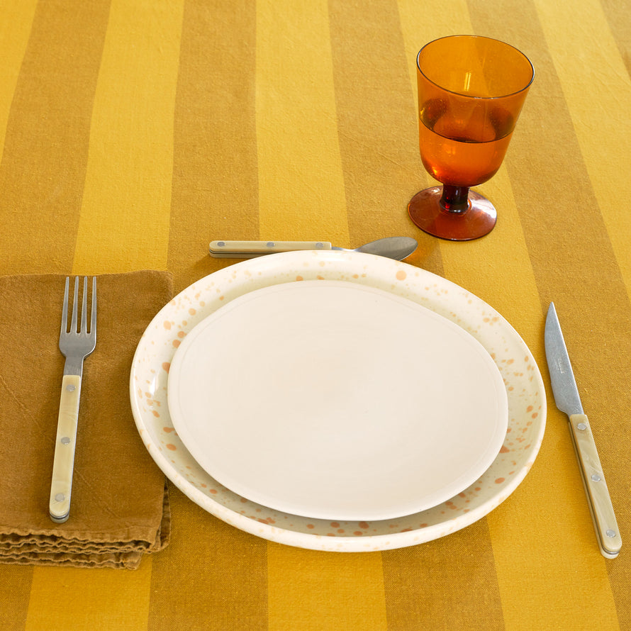 Placesetting with Stemmed Wine Glass in Amber on yellow striped tablecloth.