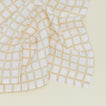 Detail of block printed napkin with a grid pattern in tan.