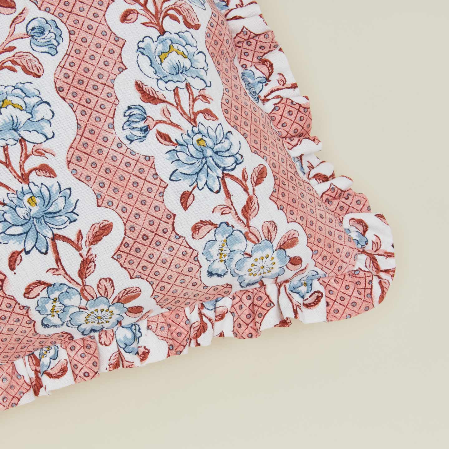 Detail of block printed floral ruffled pillow in blush.