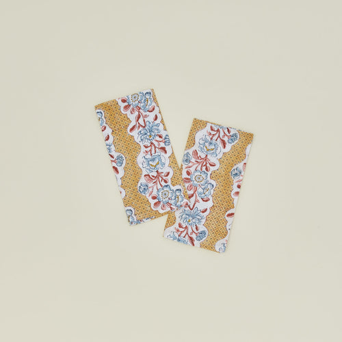 A set of two block printed napkins with a floral pattern in mustard.