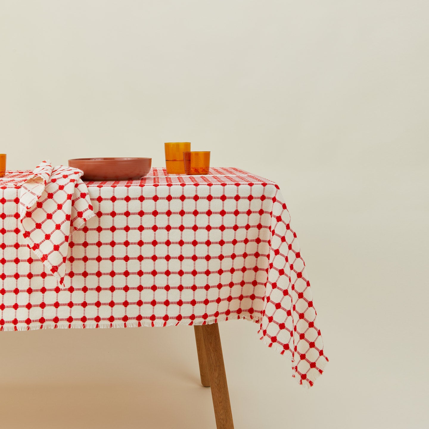 Dove and Donkey wicker fringed tablecloth in cherry on table with place setting