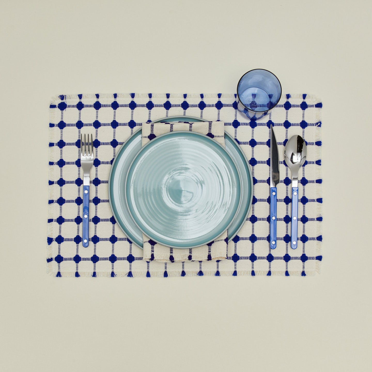 Dove and Donkey wicker fringed placemat in cobalt with place setting 