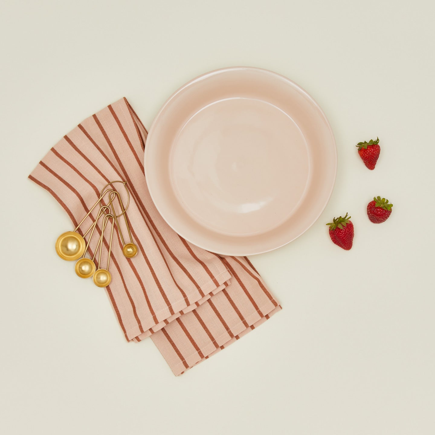Essential pie dish in blush with strawberries, measuring spoons, and dish towel