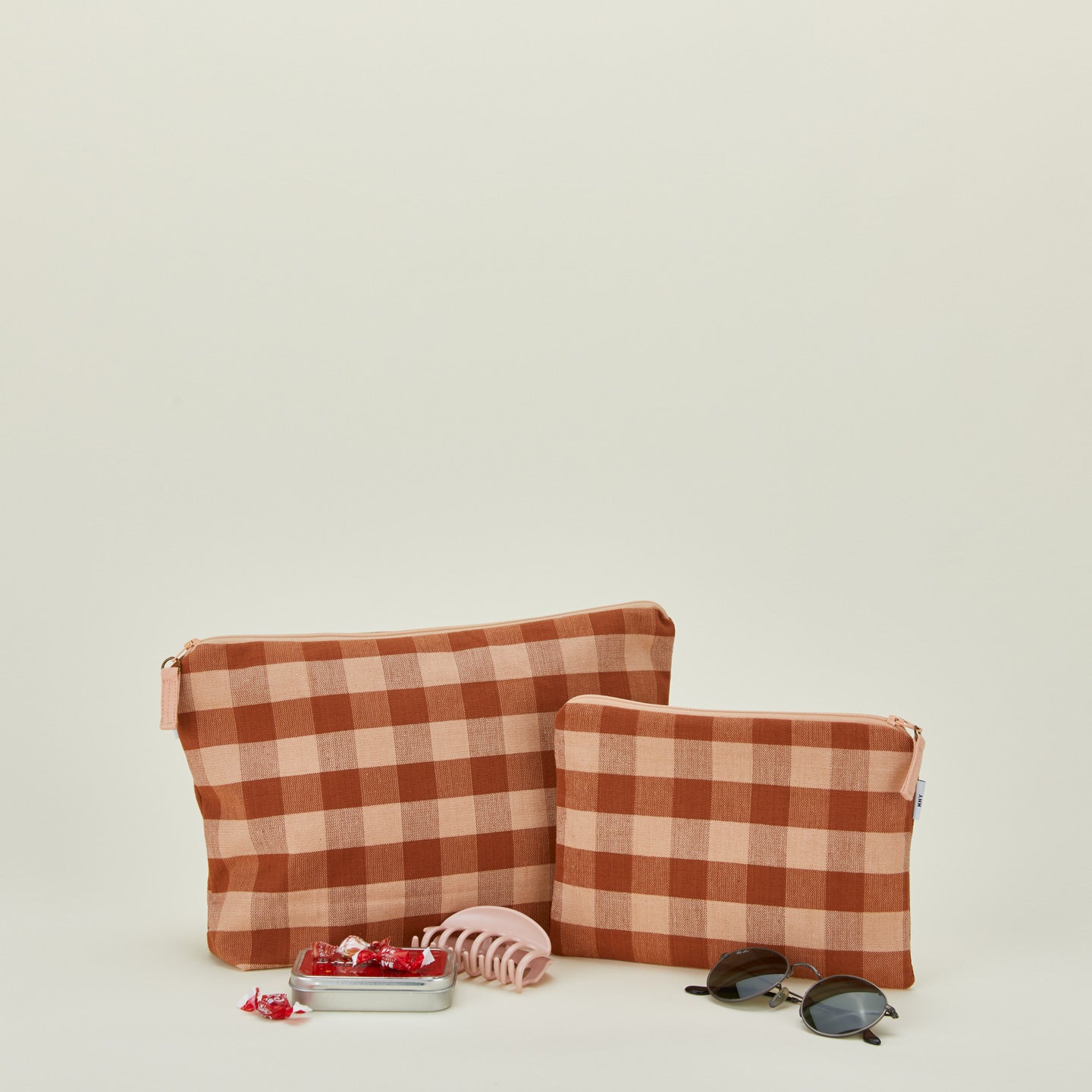 Essential gingham pouches in blush and terracotta with sunglasses, hair clip, and candy