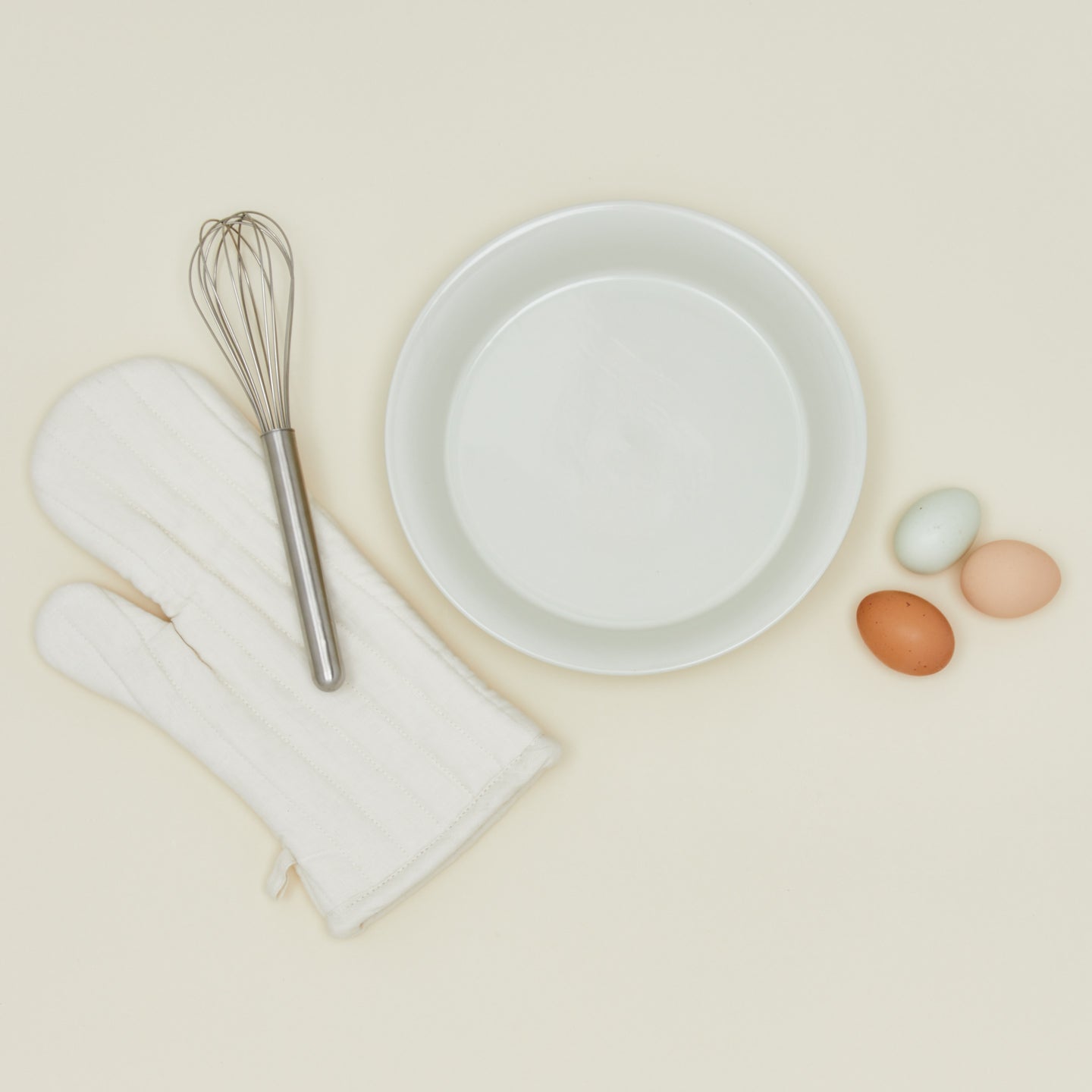pie dish in bone with eggs oven mitt and whisk