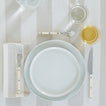 Placesetting with Essential Dinner Plate in Bone on ivory striped tablecloth.