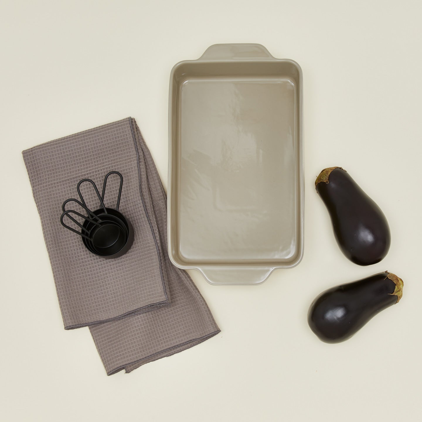 9" x 13" essential bakeware in light grey with eggplant, measuring cups, and dish towels
