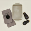 9" x 13" essential bakeware in light grey with eggplant, measuring cups, and dish towels