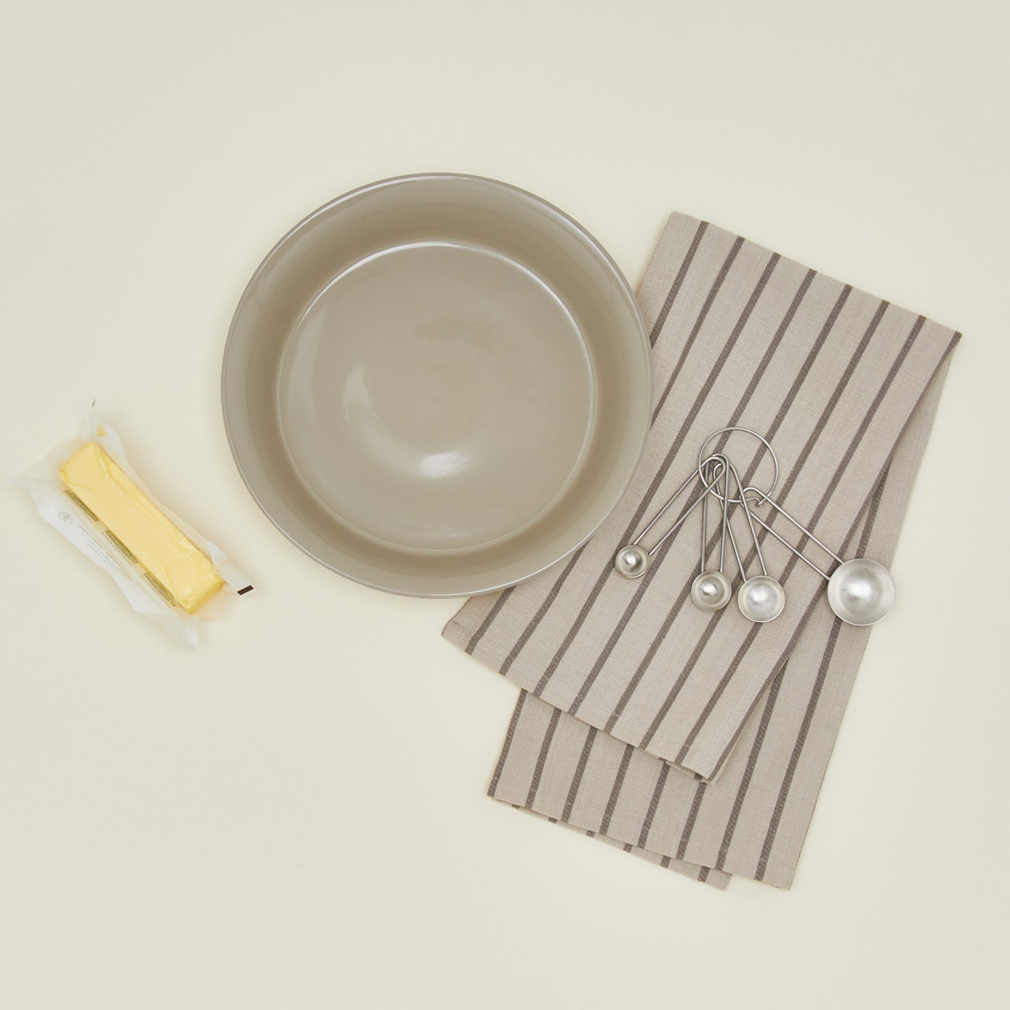 pie dish in light grey with butter, dish towel, and measuring spoons