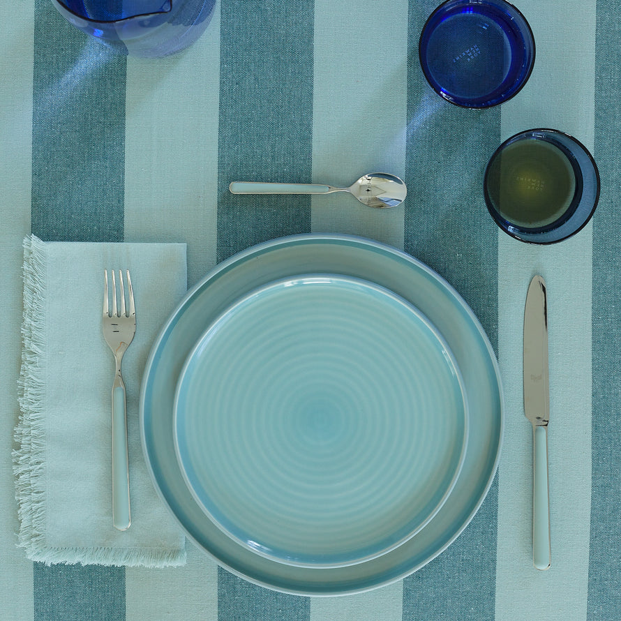 Placesetting with Essential Dinner Napkin in Sky on blue striped tablecloth.