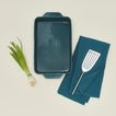9x13 bakeware with green onions dishtowel and fish spatula