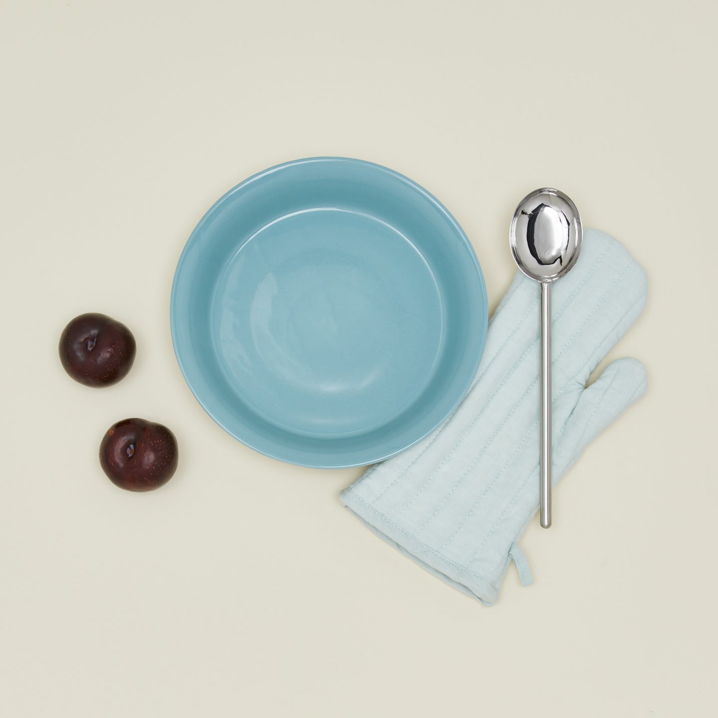 Pie dish in sky with plums oven mitt and spoon