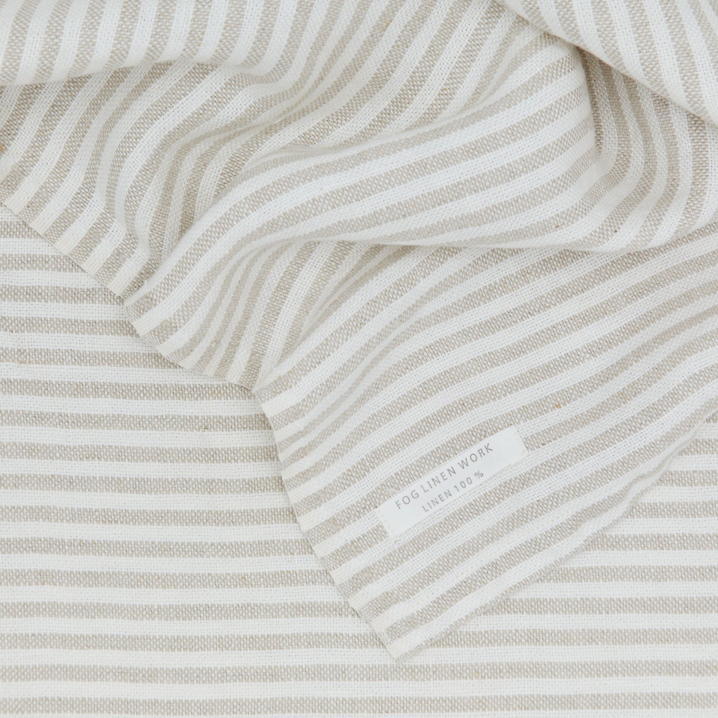 A close up of a chambray linen throw with white stripes.