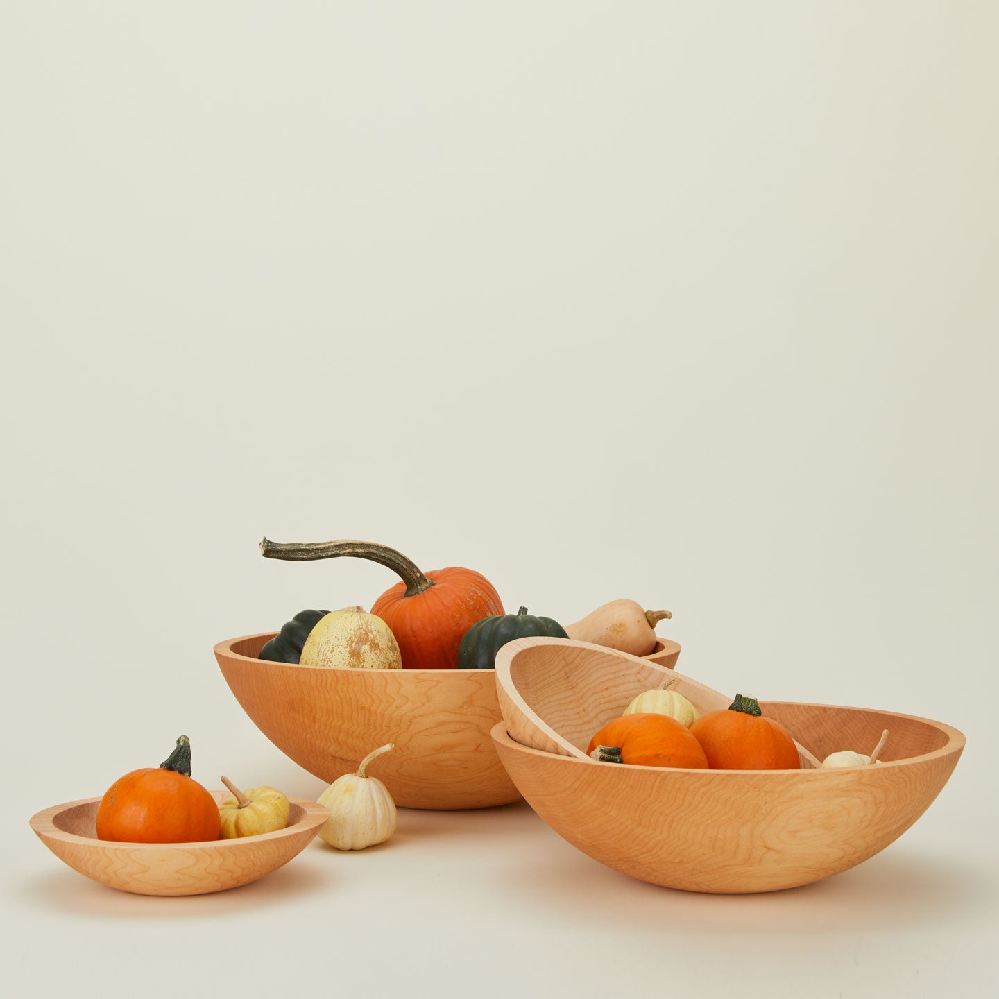 A group of maple wood bowls in four sizes, with pumpkins.