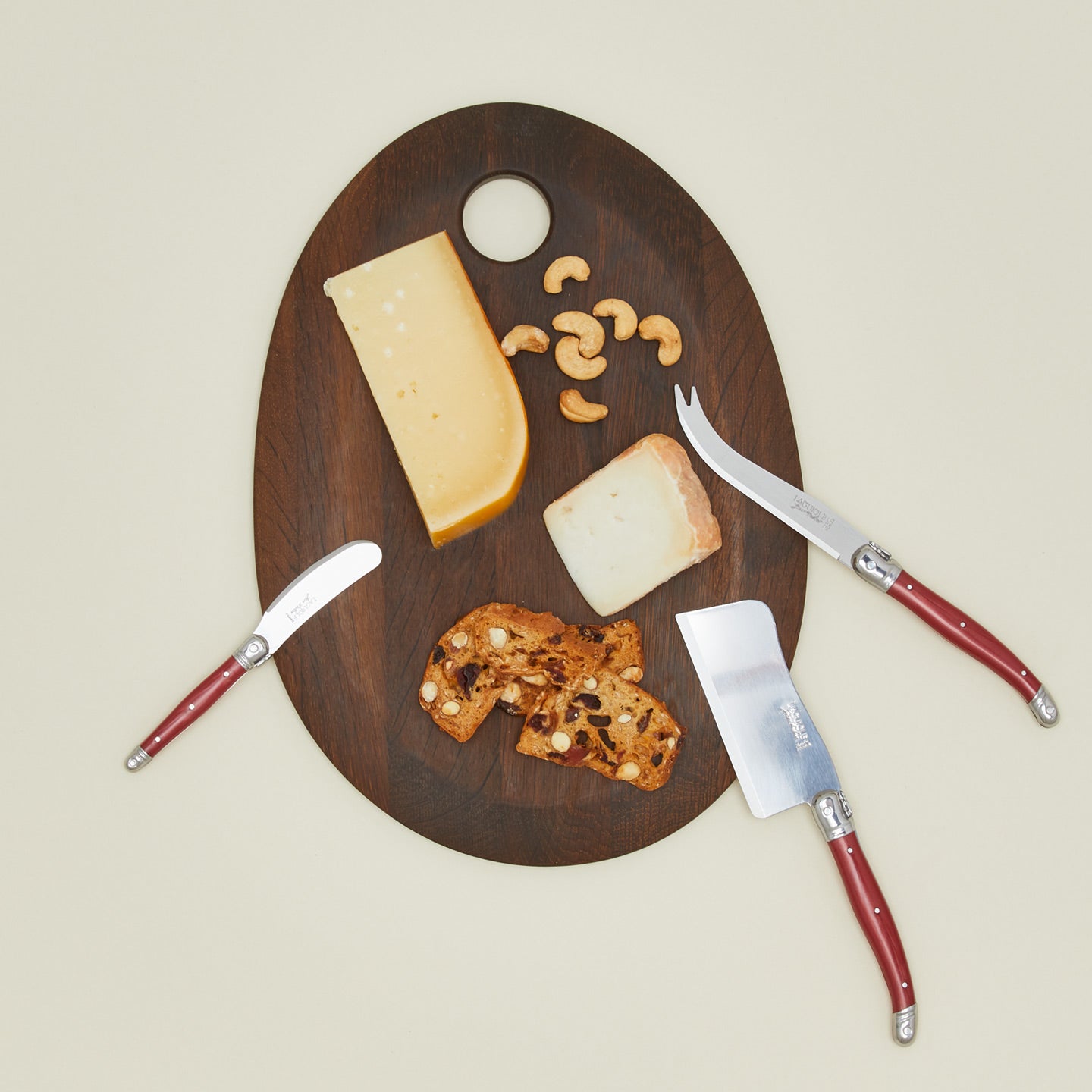 Jean Dubost Cheese knives on charcuterie board with cheese, cashews, and bread.