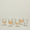 Six Artois wine glasses, some with wine.