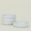 A set of four white ceramic bowls stacked in a column except for one, which is lying adjacent.