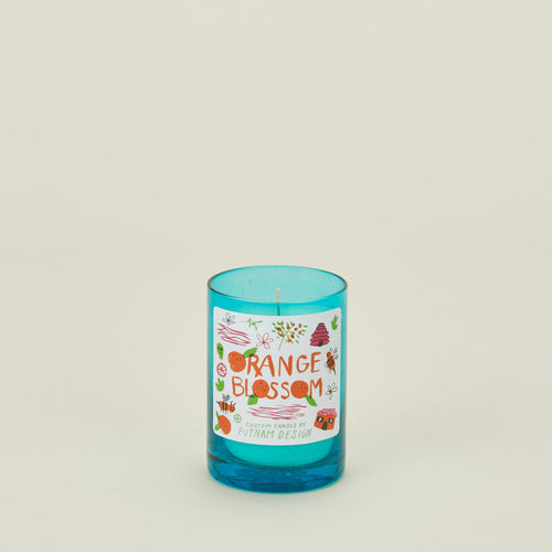 Blue candle with a decorative label on a light beige background
