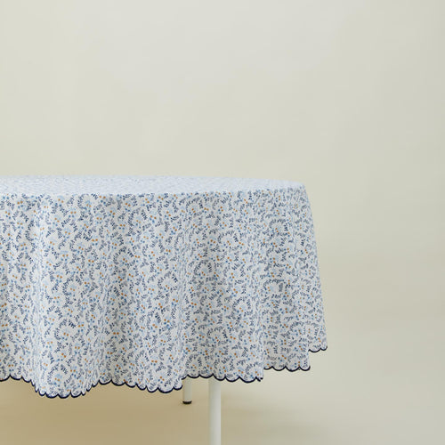 Little flowers round tablecloth in blue on table.