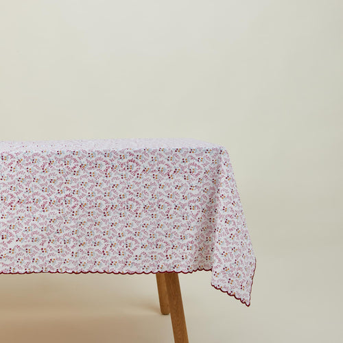 Little flowers rectangular tablecloth in maroon on table.