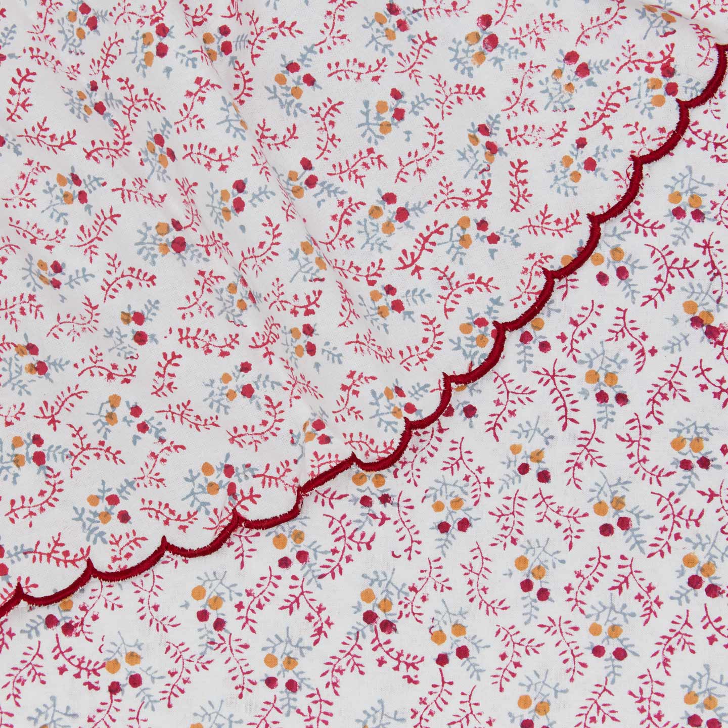 Close up view of little flowers round tablecloth in maroon.