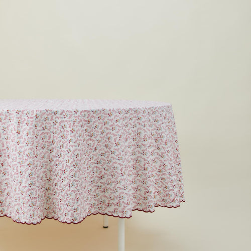Round little flowers tablecloth in maroon on table.