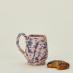 Splatter mug in pink and blue with coffee and cookie