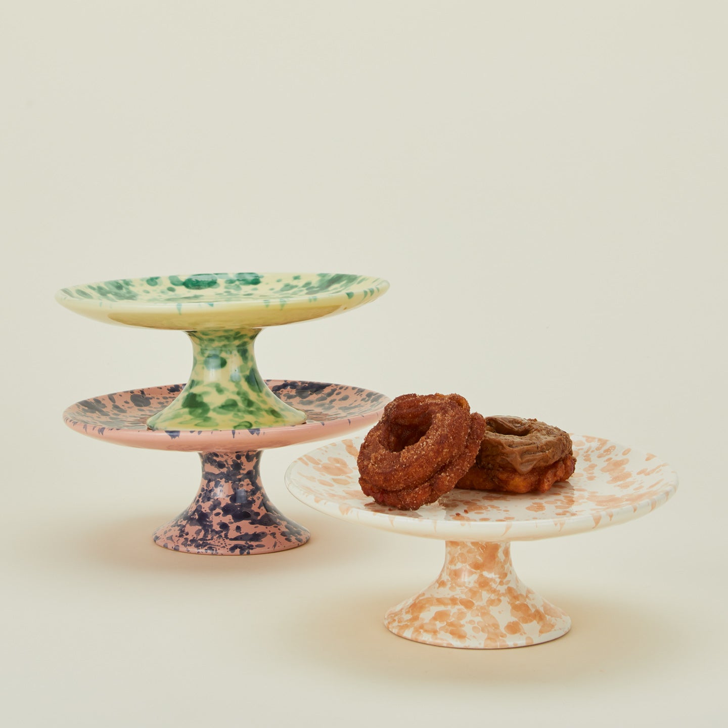 Splatter cake stands in various colors with donuts