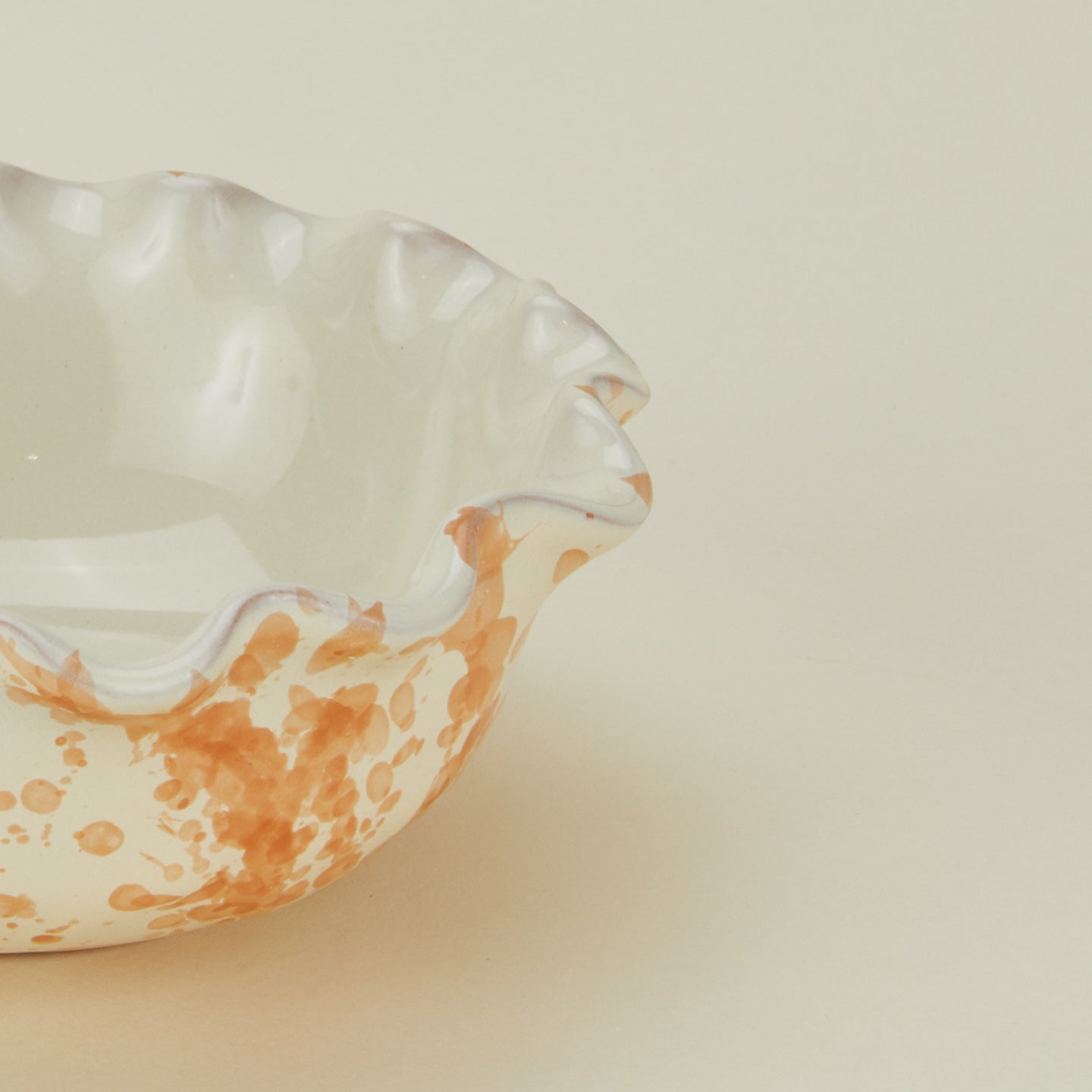 Close up view of Splatter scallop bowl in tan and ivory