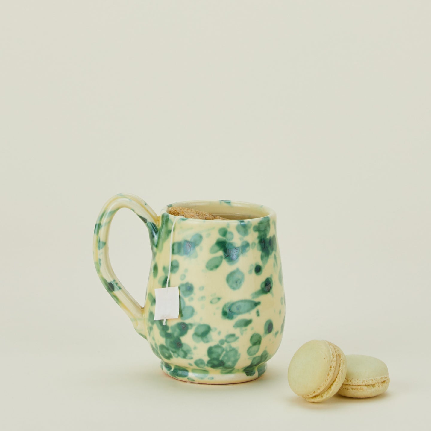 Splatter mug in yellow and green with macarons and tea