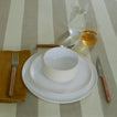 Placesetting with Simple Glasses on a green striped tablecloth.