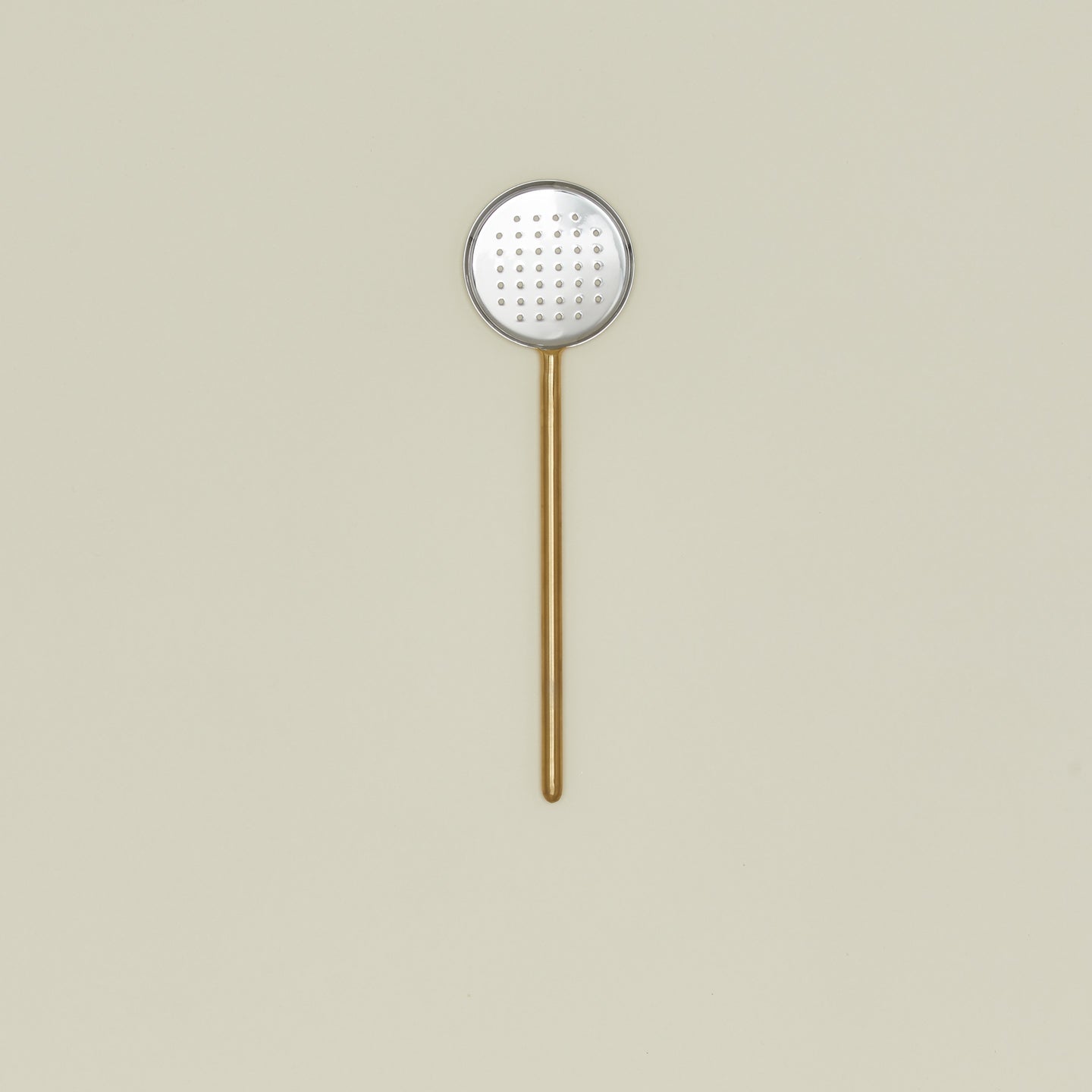 Simple metal flat slotted spoon in brass.