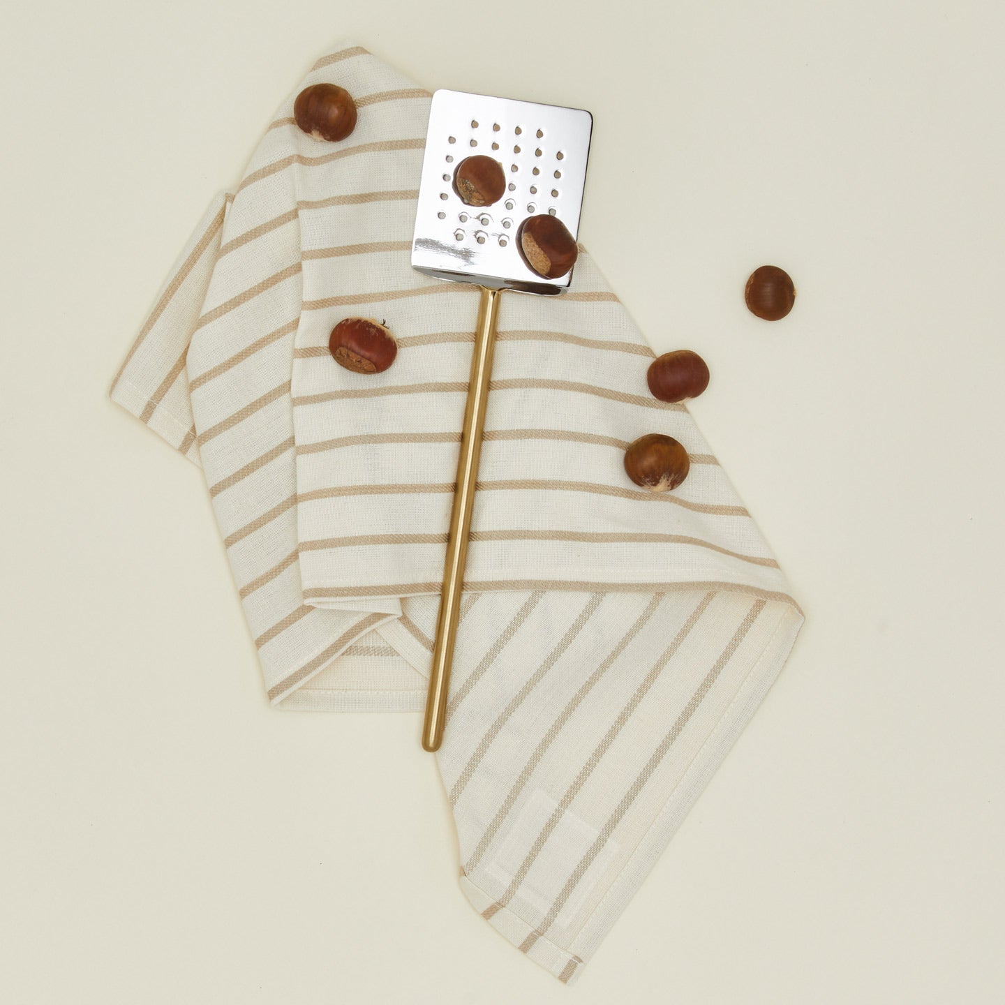 Simple metal spatula in brass with dishtowel and brazil nuts