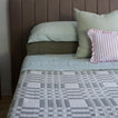 Bed with green bedding and red striped pillow.