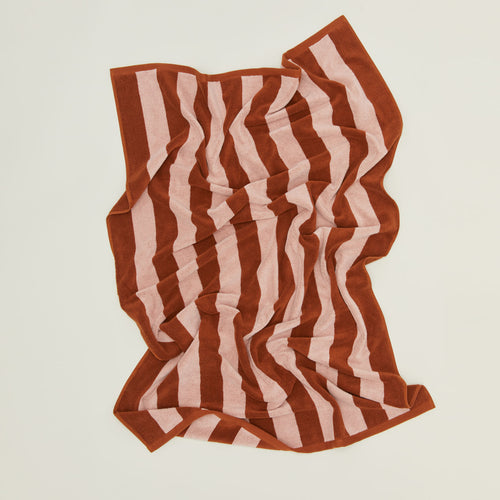 	An overhead of a striped blush and terracotta terry bath towel.