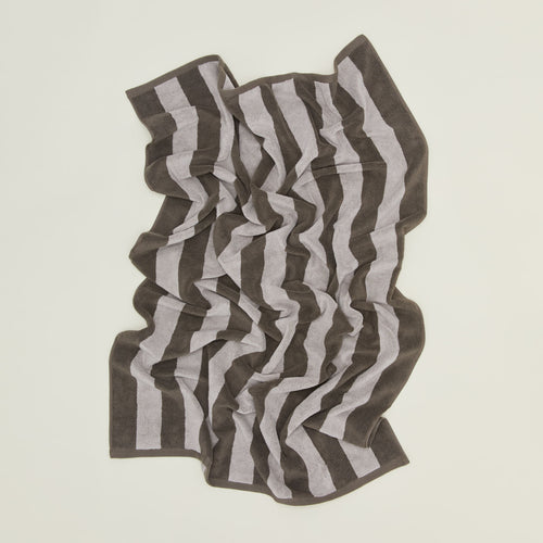 	An overhead of a striped light grey and dark grey terry bath towel.