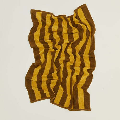 	An overhead of a striped mustard and bronze terry bath towel.