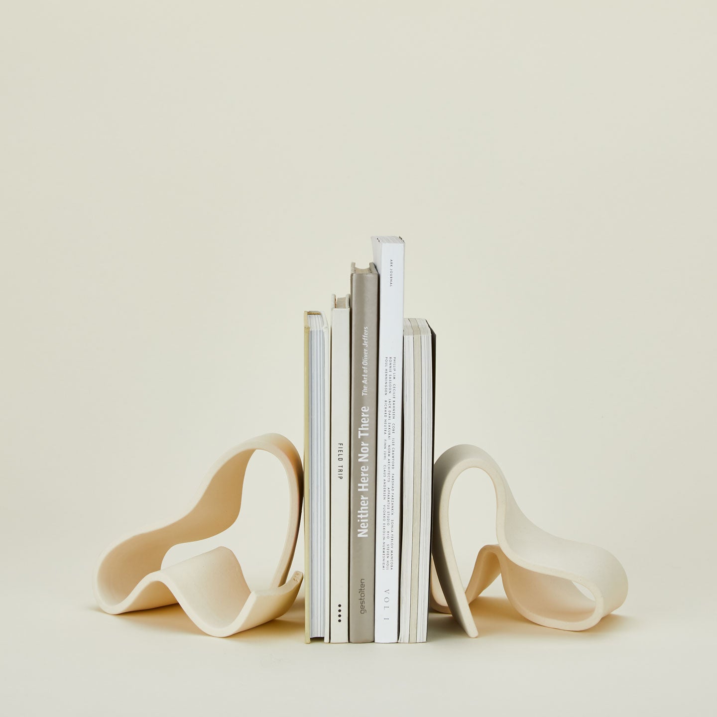 Organically shaped neutral stoneware bookends with books.