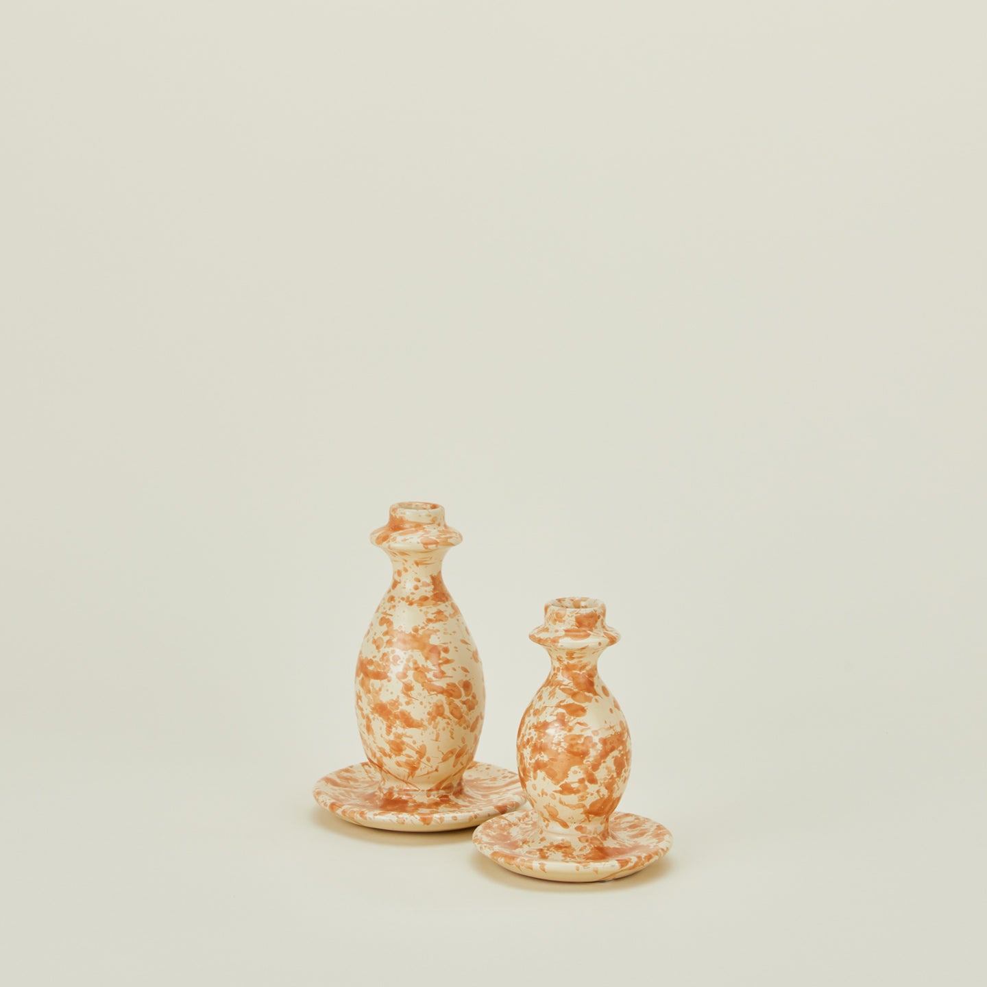 Large and small splatterware candlestick holders in ivory and bronze