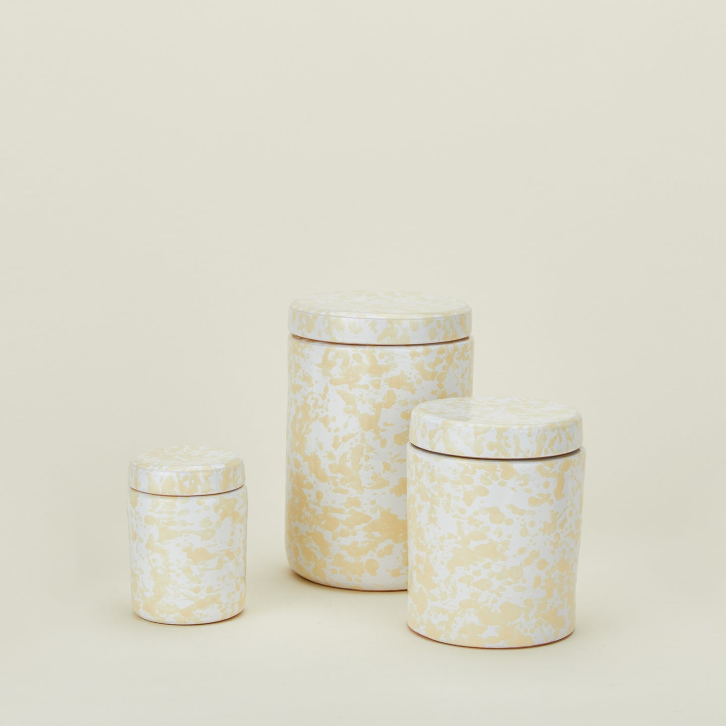 Large, medium, and small splatterware canisters in white and ivory