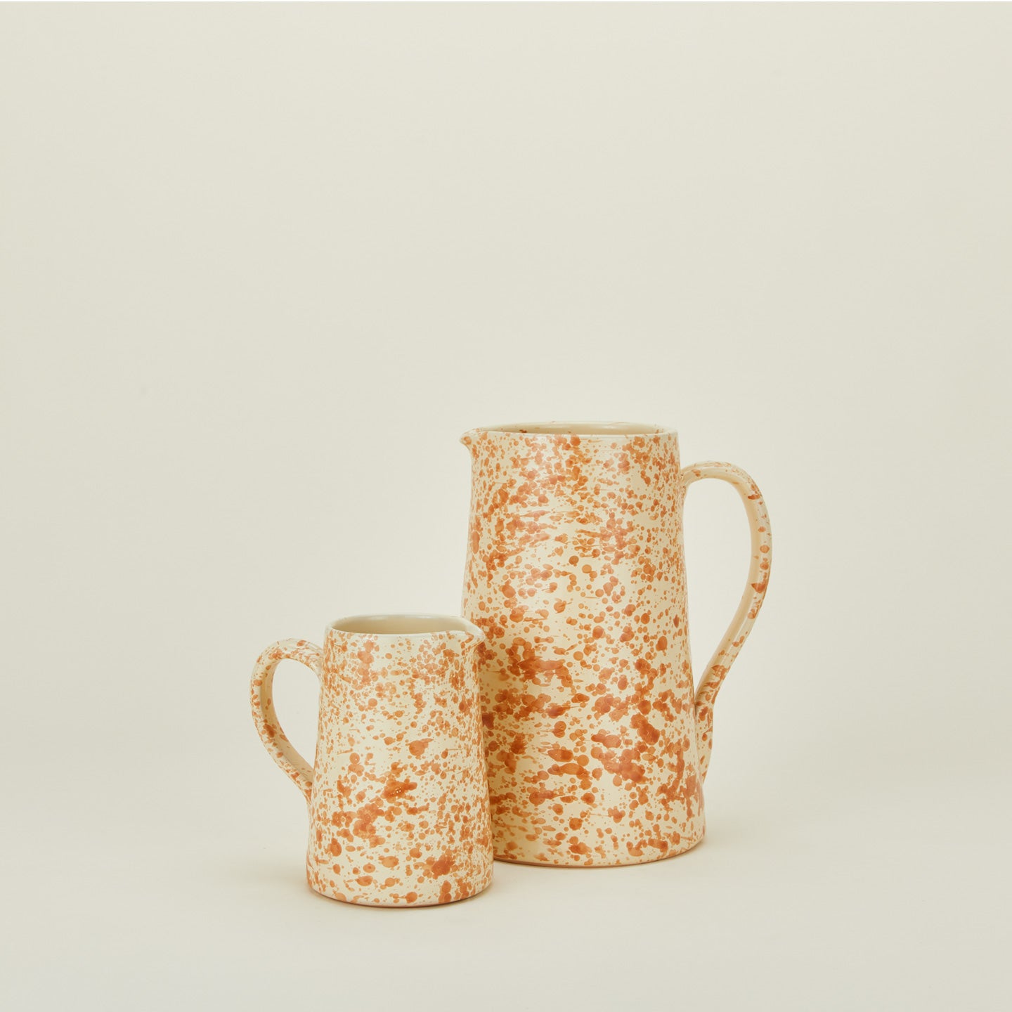 Large and small splatterware pitchers in ivory and bronze