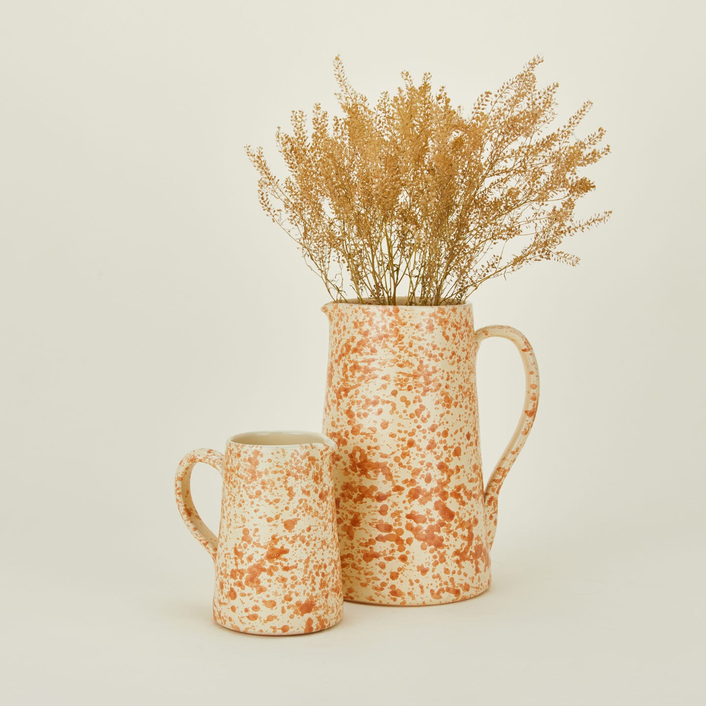 Large and small splatterware pitchers in ivory and bronze with florals
