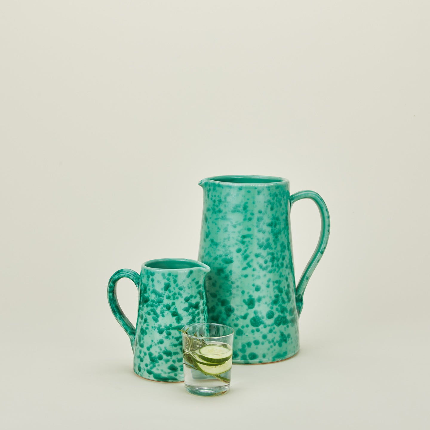 Large and small splatterware pitchers in sage and green with glass