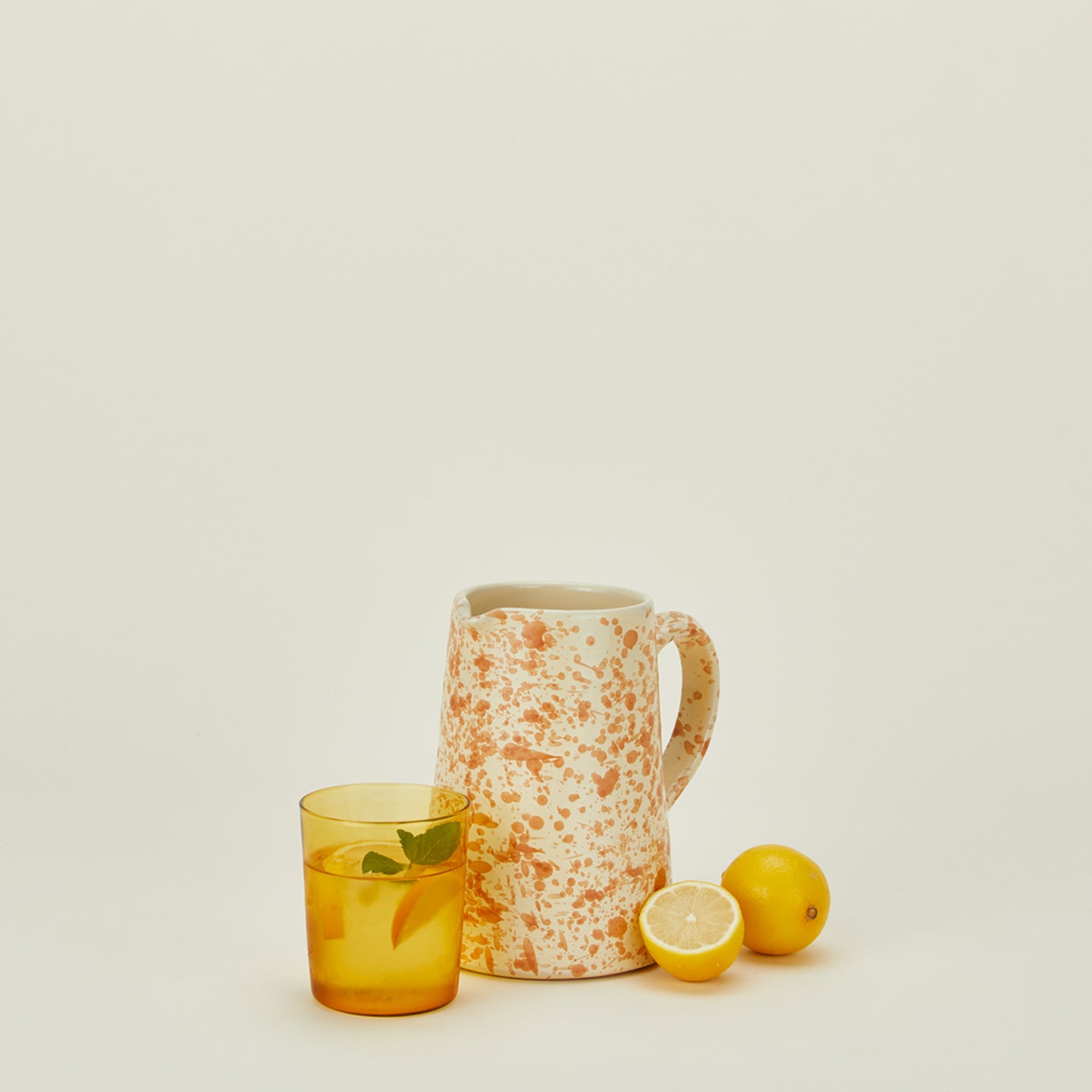 Small splatterware pitcher in ivory and bronze with glass and lemons