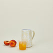 Small splatterware pitcher in white and ivory with juice and peach