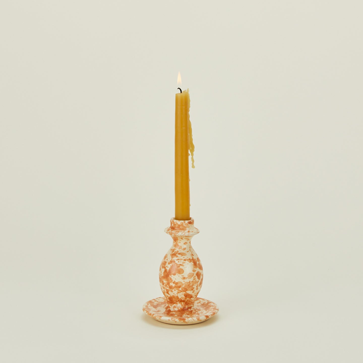 Small splatterware candlestick holder in ivory and bronze with candle