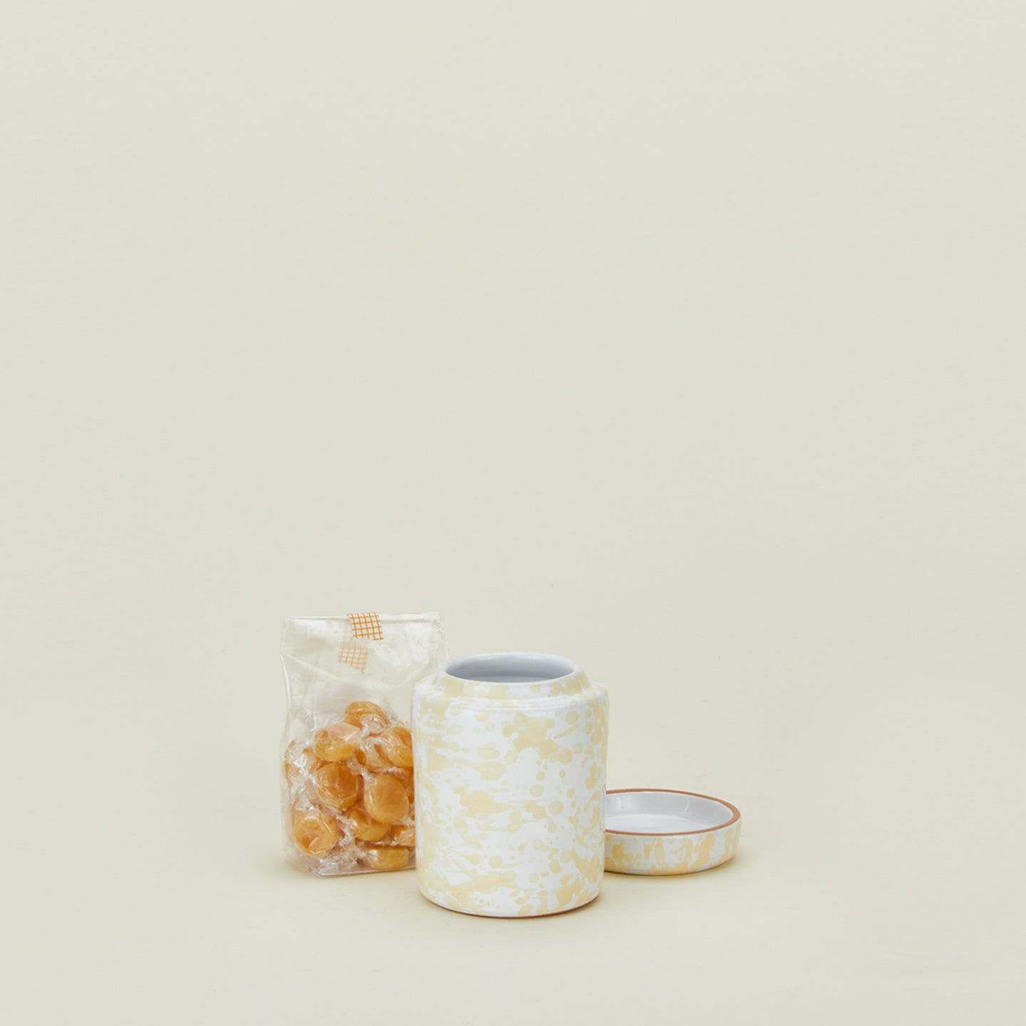 Small splatterware canister in white and ivory with candy