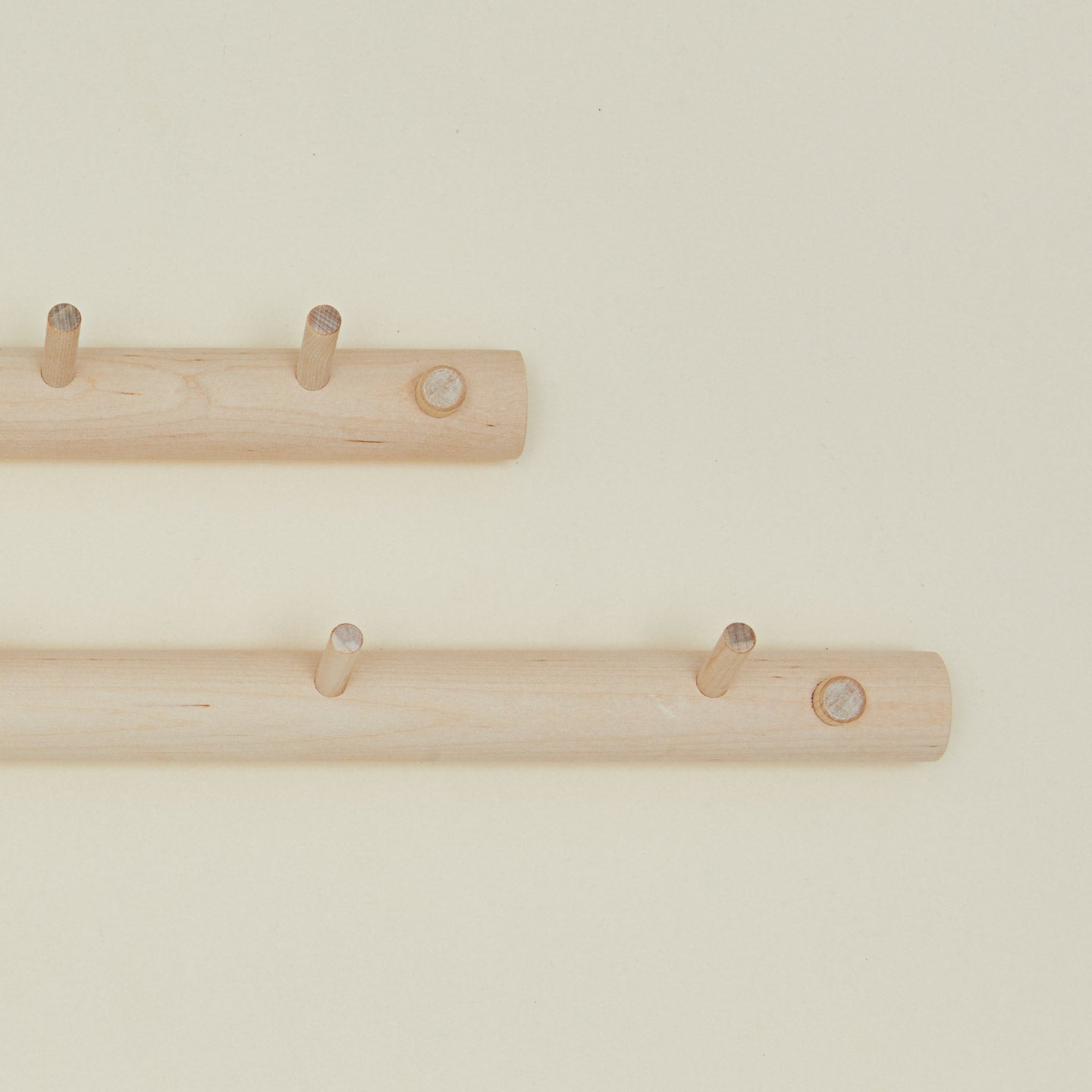Close up of two wooden coat racks with multiple hooks on a beige background