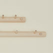 Close up of two wooden coat racks with multiple hooks on a beige background
